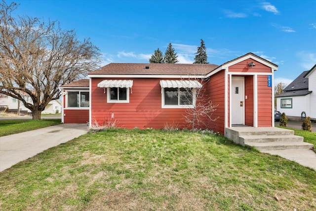 bungalow with a front yard and a shingled roof