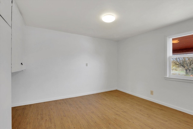 spare room featuring light wood-style floors and baseboards