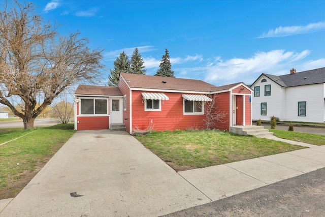 view of front of home with concrete driveway, entry steps, and a front lawn