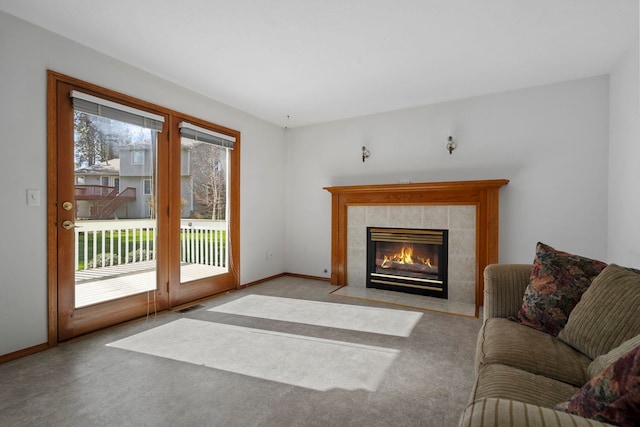 living room featuring a tile fireplace, carpet flooring, baseboards, and visible vents