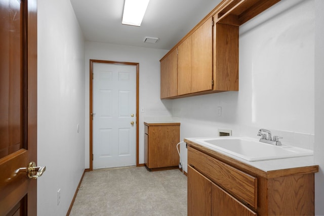 washroom with baseboards, cabinet space, hookup for a washing machine, light floors, and a sink