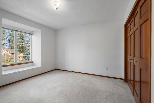 unfurnished bedroom featuring a closet, baseboards, carpet flooring, and a textured ceiling