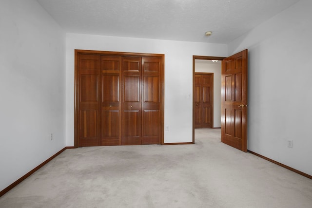 unfurnished bedroom featuring a closet, light colored carpet, and baseboards