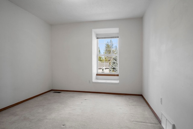 spare room with light colored carpet, baseboards, and visible vents