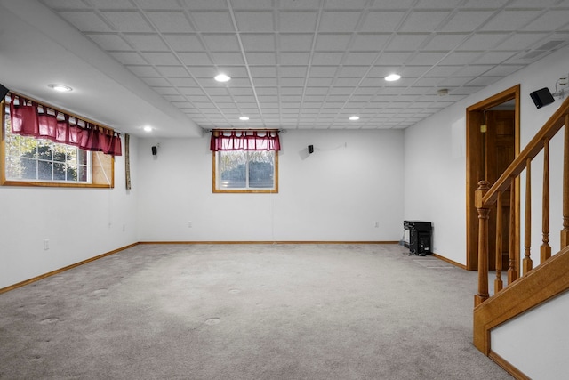 basement with carpet floors, a wood stove, recessed lighting, and stairs