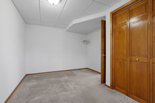 unfurnished bedroom featuring a paneled ceiling, light colored carpet, and baseboards