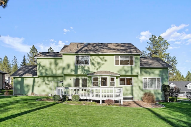 back of property with a deck, a lawn, and stucco siding