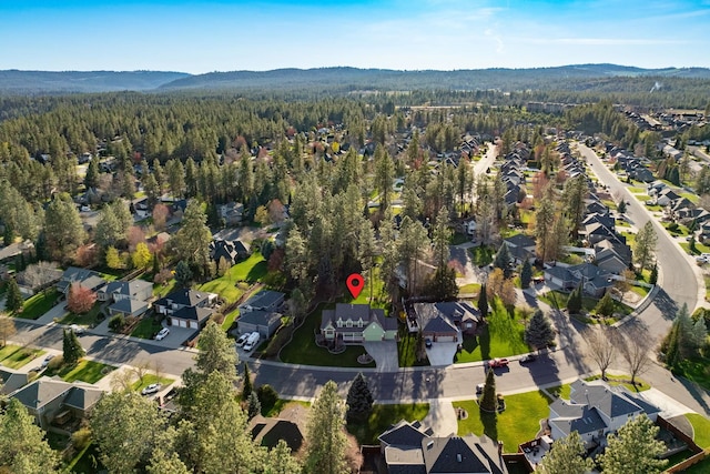 drone / aerial view with a wooded view, a mountain view, and a residential view