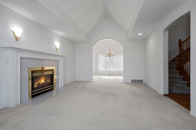 unfurnished living room with a chandelier, a high end fireplace, visible vents, and carpet floors