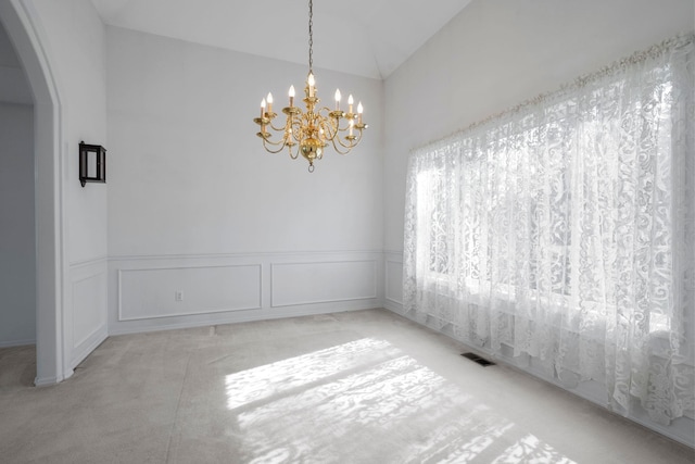 interior space featuring a chandelier, visible vents, wainscoting, arched walkways, and carpet