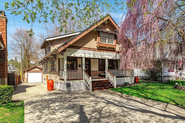 view of front of property featuring a porch, concrete driveway, a garage, an outdoor structure, and a front yard