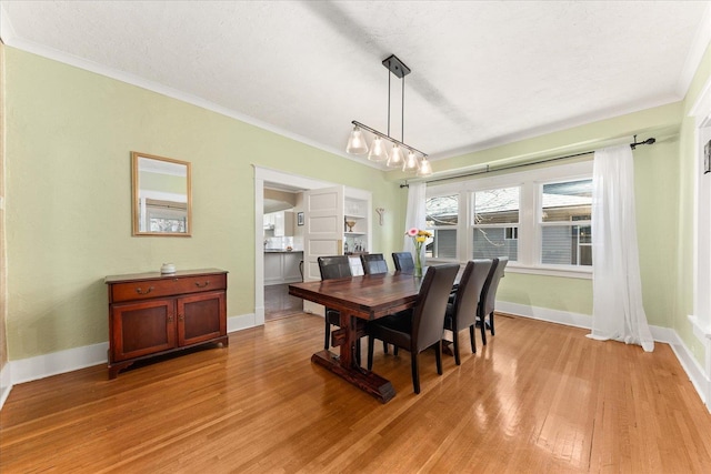 dining space with baseboards, ornamental molding, a textured ceiling, and light wood-type flooring