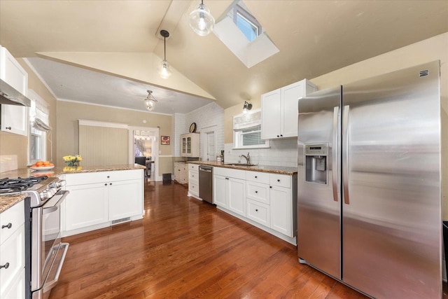 kitchen with vaulted ceiling with skylight, a sink, stainless steel appliances, white cabinets, and a peninsula