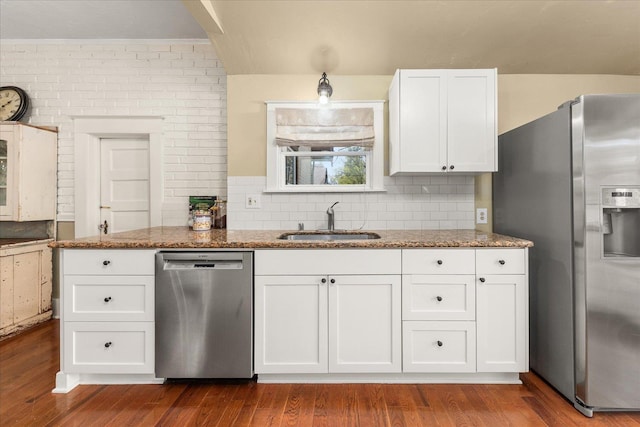 kitchen featuring stone counters, white cabinets, stainless steel appliances, and a sink