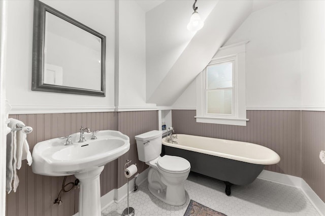 bathroom with lofted ceiling, a wainscoted wall, a freestanding bath, and toilet