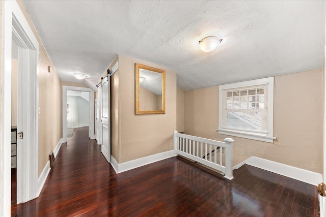 interior space with hardwood / wood-style floors, baseboards, a textured ceiling, and a barn door