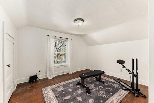 workout area with vaulted ceiling, baseboards, and wood finished floors