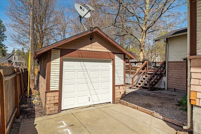 detached garage featuring concrete driveway and fence