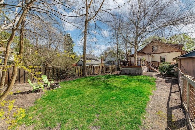 view of yard featuring a wooden deck, a fenced backyard, and a fire pit
