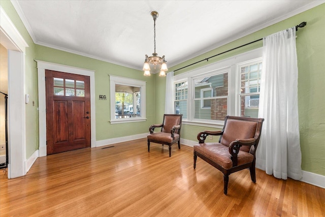 living area with light wood-type flooring, baseboards, visible vents, an inviting chandelier, and crown molding