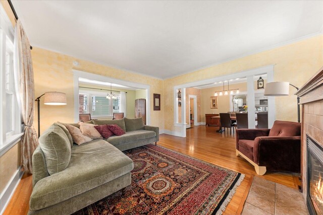 living room featuring baseboards, wood finished floors, a chandelier, and crown molding