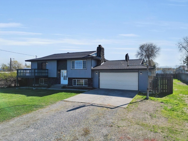 raised ranch with a chimney, fence, a front lawn, an attached garage, and driveway