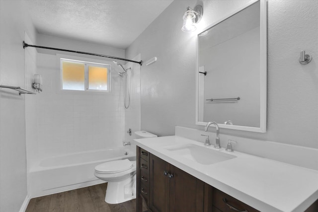 full bath with shower / washtub combination, wood finished floors, toilet, vanity, and a textured ceiling