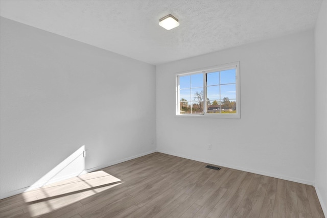 spare room featuring baseboards, wood finished floors, and visible vents