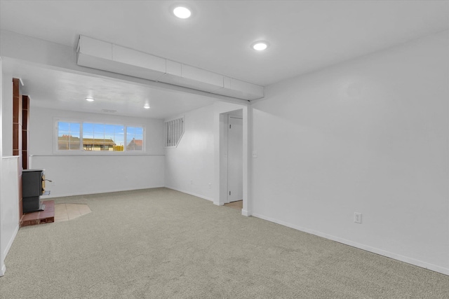 basement with baseboards, carpet floors, a wood stove, and recessed lighting