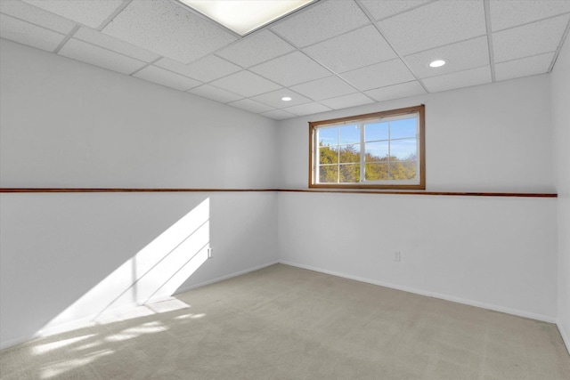 empty room with baseboards, recessed lighting, light colored carpet, and a drop ceiling