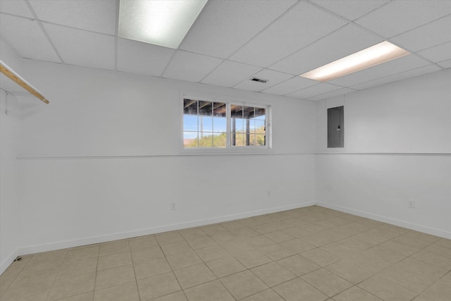 below grade area with baseboards, visible vents, electric panel, and a drop ceiling