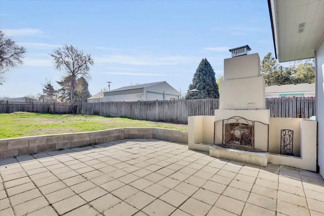 view of patio featuring a fenced backyard and an outdoor brick fireplace