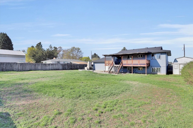 rear view of property with fence, stairs, an outdoor structure, and a yard