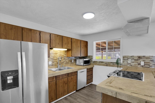 kitchen featuring tasteful backsplash, a textured ceiling, a sink, stainless steel appliances, and light countertops