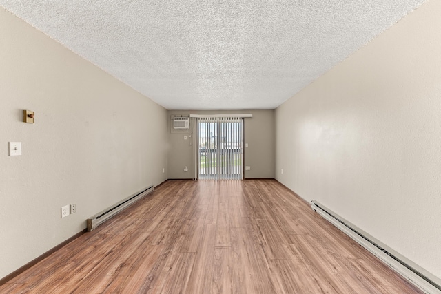2310 E 1st Ave, Spokane, WA 99202 - spare room with a baseboard heating unit, a wall mounted AC, light wood-style flooring, and a textured ceiling