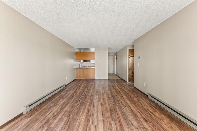 2310 E 1st Ave, Spokane, WA 99202 - unfurnished living room featuring a baseboard heating unit, wood finished floors, and a textured ceiling