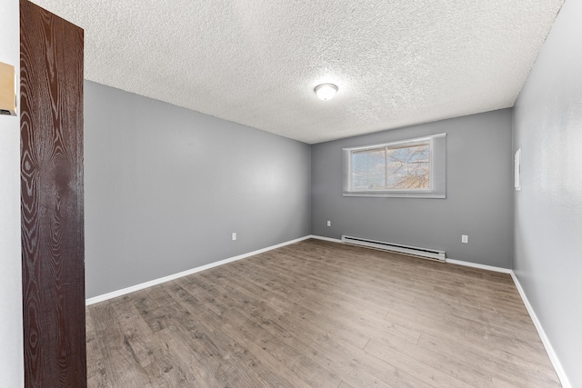 2310 E 1st Ave, Spokane, WA 99202 - spare room featuring a baseboard radiator, wood finished floors, a textured ceiling, and baseboards