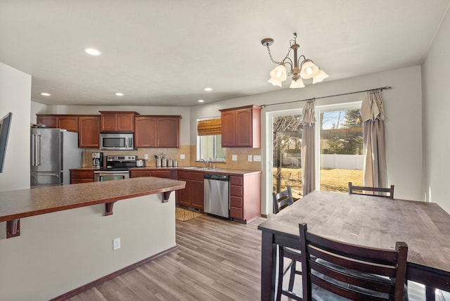 112 S Holiday Rd, Spokane Valley, WA 99016 - kitchen with light wood-style floors, a breakfast bar, an inviting chandelier, a healthy amount of sunlight, and stainless steel appliances