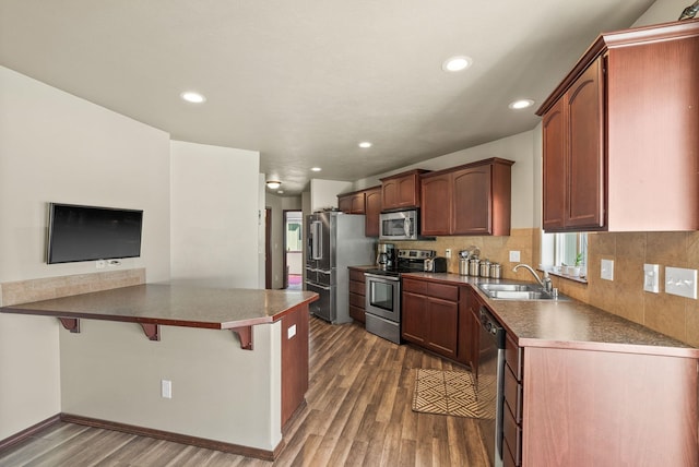 112 S Holiday Rd, Spokane Valley, WA 99016 - kitchen featuring stainless steel appliances, a sink, dark wood-style flooring, recessed lighting, and a kitchen bar