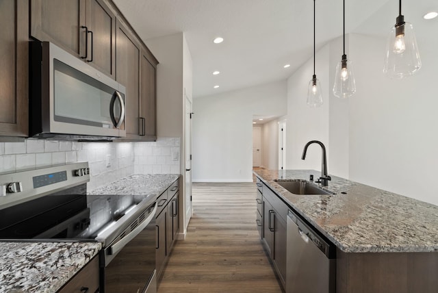 kitchen featuring a sink, a center island with sink, dark brown cabinetry, dark wood-type flooring, and appliances with stainless steel finishes