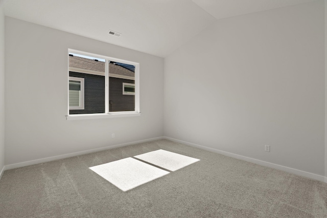 carpeted empty room featuring lofted ceiling, baseboards, and visible vents