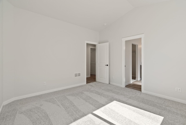 unfurnished bedroom featuring carpet floors, lofted ceiling, visible vents, and baseboards