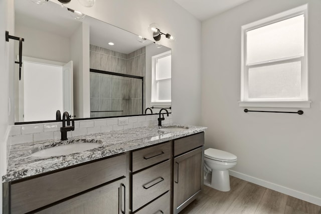 full bath featuring toilet, baseboards, a sink, and a stall shower
