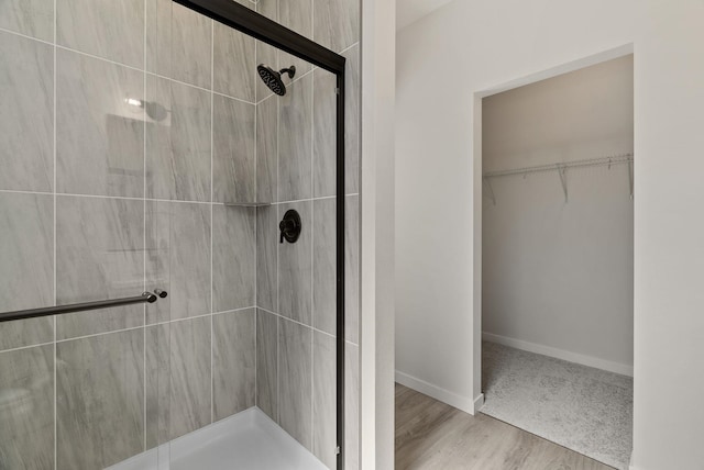 full bathroom with baseboards, a spacious closet, and a stall shower