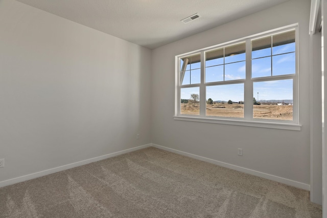 carpeted spare room with baseboards and visible vents