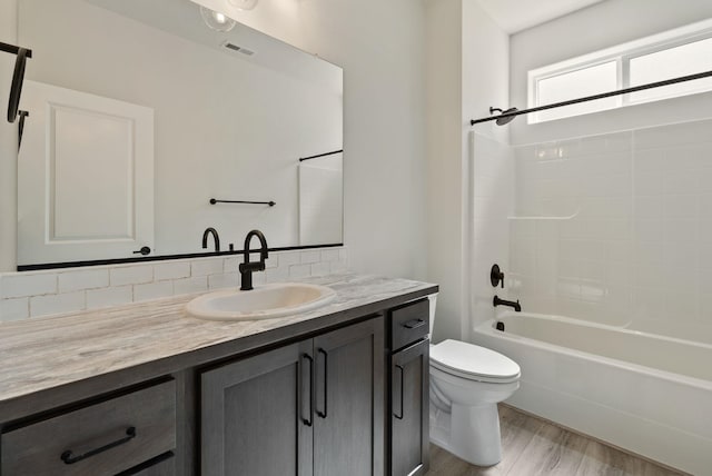 full bathroom with toilet, visible vents, backsplash, wood finished floors, and vanity