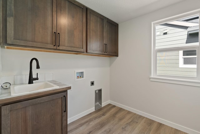 clothes washing area with a sink, baseboards, hookup for a washing machine, cabinet space, and electric dryer hookup