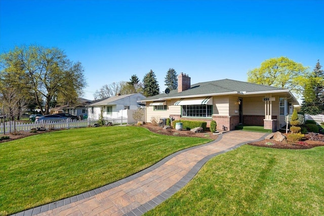 rear view of house featuring fence, a lawn, a chimney, and brick siding