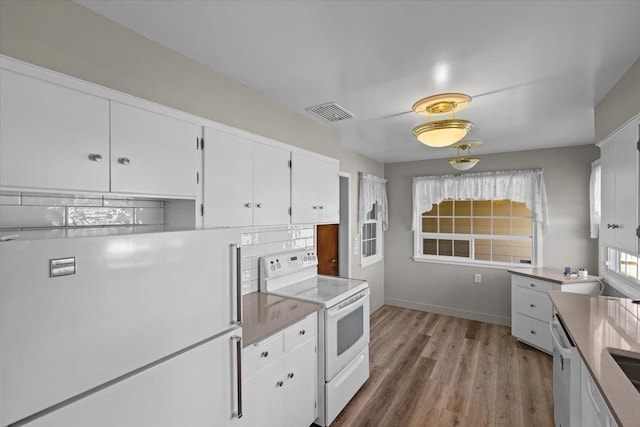 kitchen with white cabinets, visible vents, white appliances, baseboards, and light wood-style flooring