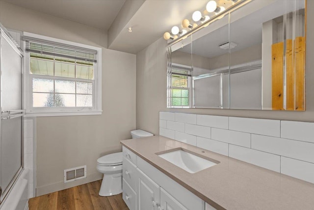 bathroom with toilet, visible vents, backsplash, wood finished floors, and vanity